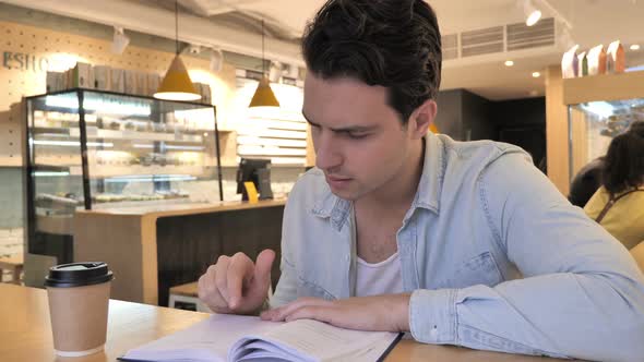 Relaxing Young Man Reading Book in Cafe