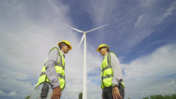 Teamwork of Asian windmill engineer group, worker working, shaking hands on site at wind turbines