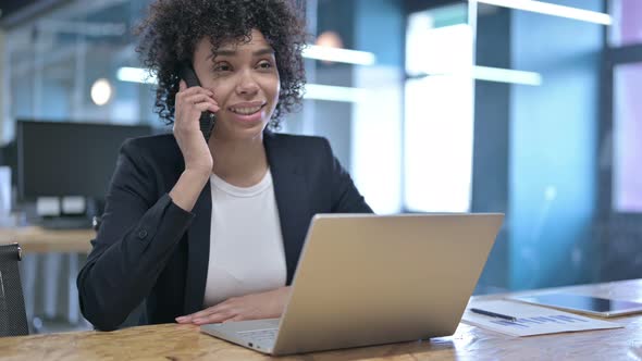 Cheerful African Businesswoman Talking on Smartphone at Work