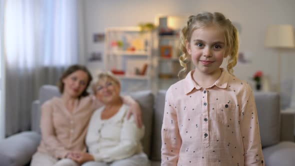 Smiling Girl Looking in Camera With Mother and Granny on Background, Generations