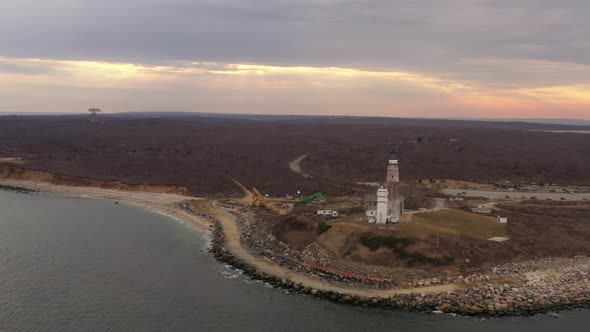 An aerial view of the Montauk lighthouse during a cloudy sunset. The drone camera truck left and pan