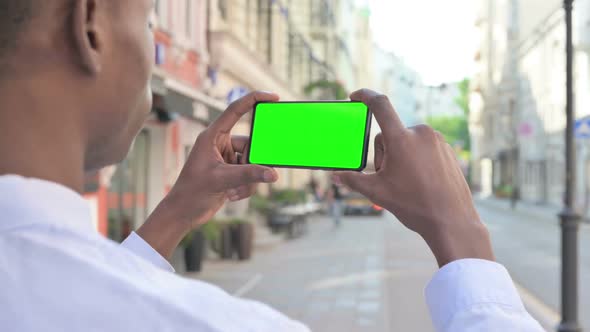 African Man Looking at Smartphone with Green Chroma Screen