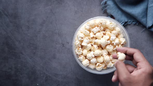 Young Man Eating Popcorn From a Container on Black Background