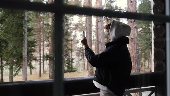 Attractive Young Woman Drinks Tea or Coffee on the Balcony Against the Background of the Forest. She