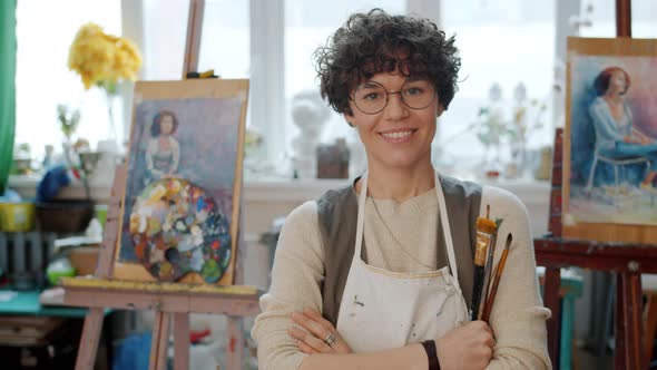 Slow Motion Portrait of Pretty Girl Artist Standing in Art Studio Holding Paintbrushes