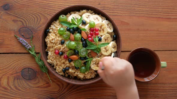 Wholegrain Oatmeal porridge with fresh berries, fruits, nuts, mint leaves in child hands