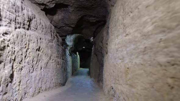 The cave is illuminated by a lantern light. Speleology, dark underground excavation tunnel.