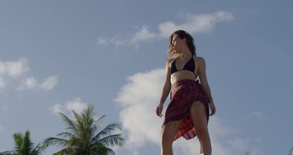 Independent Woman Stands on the Rock She Stands Against Blue Sky and Palm Trees