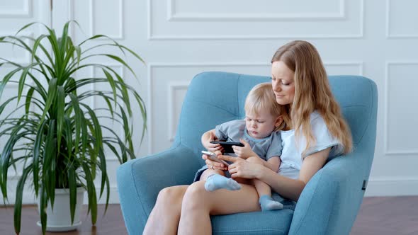 Young Mother and Son Are Enthusiastically Engaged in Online Entertainment on a Smartphone.