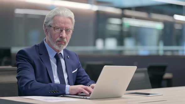 Old Businessman with Laptop Smiling at Camera