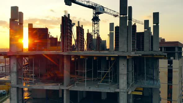 Unfinished Building and Crane on Sunset Background on Site. alt