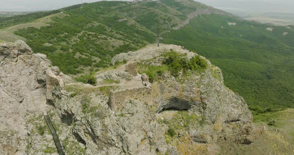 A forested scenery and an old cross on top of the Azeula Fortress ruins.