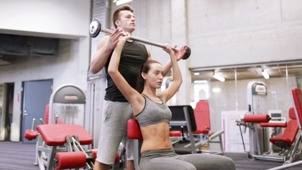 Man And Woman With Barbell Flexing Muscles In Gym