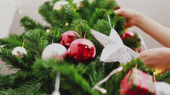 Young Asian woman holding small red balls decorate the Christmas tree.