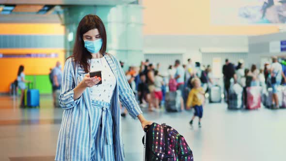 Female Air Passenger in Mask, Standing at Airport, with Luggage, Waiting To Board the Plane. She Is