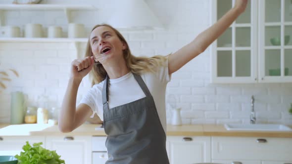 Happy Woman Sings Into the Microphone Whisk Dancing Cooking in the Kitchen