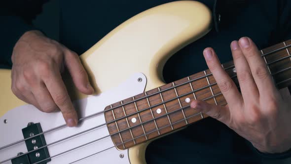 Artist Plays White Bass Guitar on Different Frets Closeup