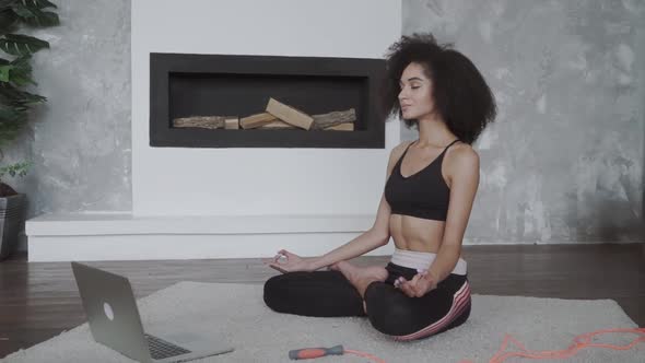 Beautiful Young Multiracial Woman Does Yoga and Strength Training Exercises on a Mat in Her Living