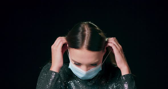 Closeup of a Teenage Caucasian Girl Wear Brocade Dress Putting on a Protective Medical Face Mask