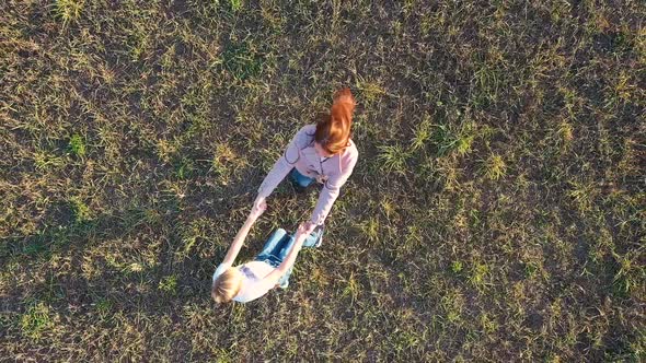 The Girl and the Guy Spin Around Held By Hands on the Field