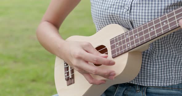 Woman Play a Song on Ukulele and Sitting on The Grass