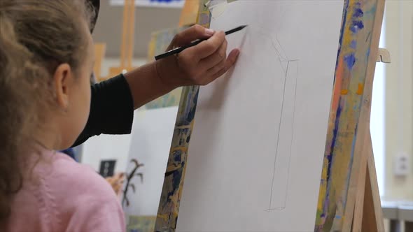 Young Hands of the Artist, Little Girl Artist Paints a Canvas with Brush,Sitting a Table and Draw on