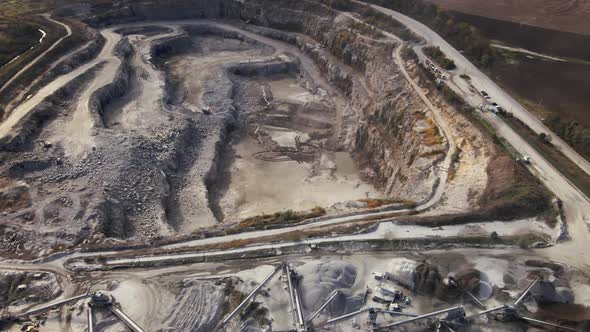 Aerial view of Slope operating granite quarry with mining equipment on ledges