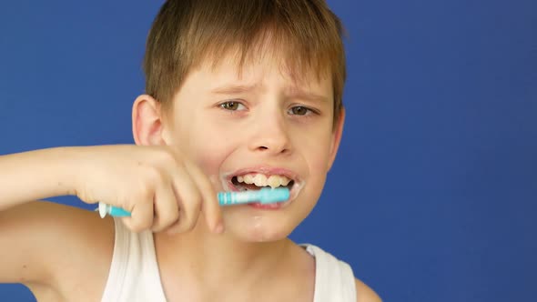 Portrait of a caucasian sleepy tired boy 7 years old brushing his teeth after sleeping.