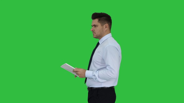 Elegant young businessman using tablet while walking on