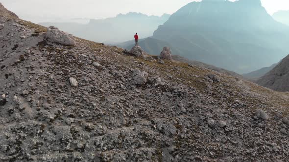 Epic Drone Unveil Shot of Man Hiker in Red Jacket Standing on Rock