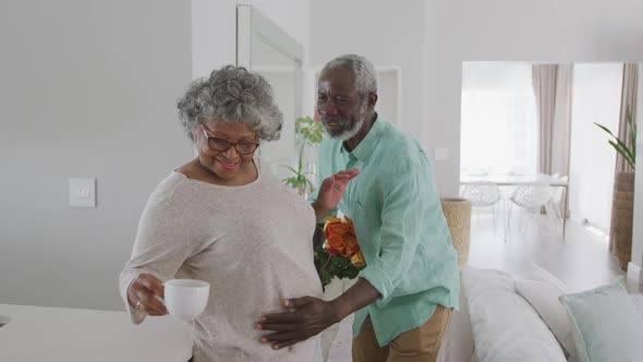 A senior African American man offering flowers to his wife