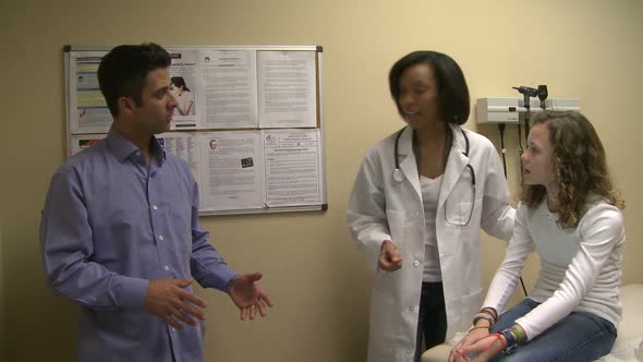 Female Doctor In Exam Room With Father And Daughter (4 Of 5)