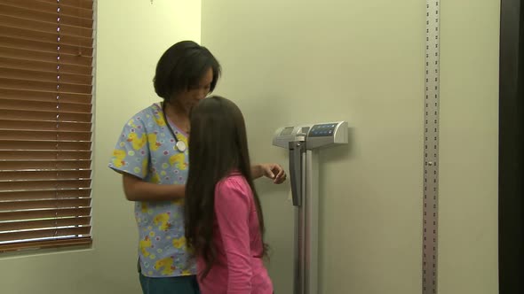 Nurse Measures Young Female Patient's Height