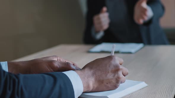 Closeup of Male Hands Arms in Office Table Writing in Notebook at Meeting Brainstorming Cropped View