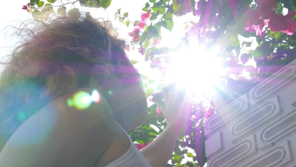 Young Girl In Sun Beams Looking At Flowers