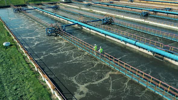 Two Wastewater Operators Walking Along the Pipes at a Sewage Cleaning Facility