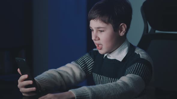 Smiling Boy 13 Years Old Making Video Call Using Smartphone While Sitting at Home Late at Night