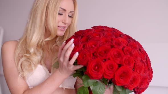 Pretty Woman In White Bra Touching A Rose Bouquet