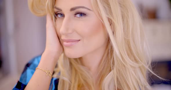 Smiling Blond Woman With Hand Touching Her Face alt