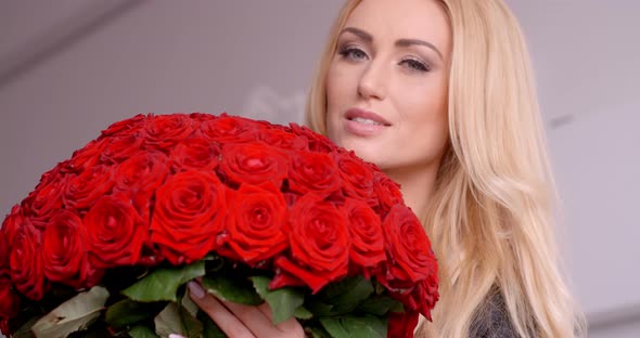 Blond Woman Holding A Bouquet Of Fresh Red Roses alt