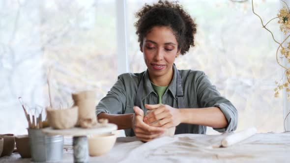 Smiling woman potter knead clay