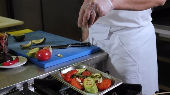 Closeup of a Chef Salting Grilled Vegetables in a Professional Kitchen
