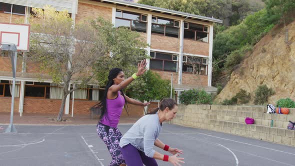 Diverse female basketball team playing match, dribbling and shooting ball