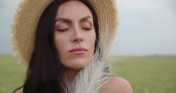 Girl In A Field In A Straw Hat Caresses Herself With A Featherbed