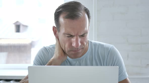 Tired Man with Neck Pain working on Laptop