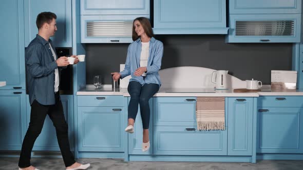 A Beautiful Girl Sitting in the Kitchen, the Guy Bringing Her a Cup of Coffee and They Drink