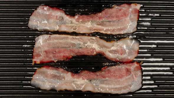 Frying A Strips Af Bacon On A Black Pan