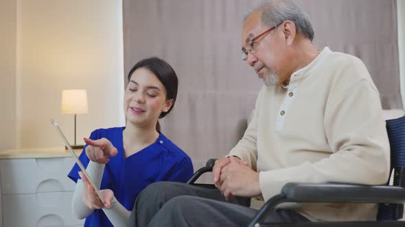 Asian Senior elderly older male patient talking to caregiver physician nurse at nursing home care.