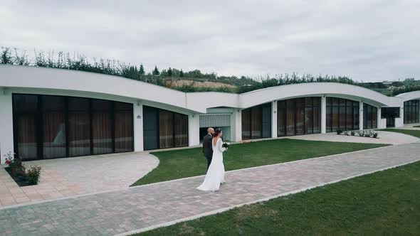 Newlyweds stroll against the backdrop of a beautiful hotel in the countryside in a modern style