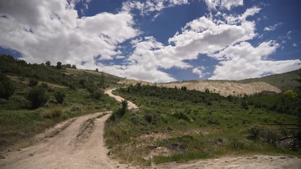 Panning view of dirt road leading up hillside to quarry